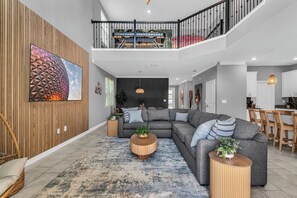 Ein modernes Wohnzimmer mit einem Ecksofa, runden Couchtischen und einem großen Wandbild.