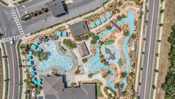 An aerial view of a resort with a large swimming pool, multiple lounge areas, and a road adjacent to the property. - Commercial Mario Arcade • Star Wars & Candy Rooms • 10 Mi Disney (Kissimmee)