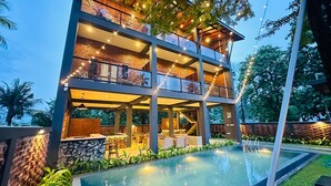 A multi-story building with a pool, outdoor seating, and string lights. - Airport Hotel Transit 98  (Katunayake)