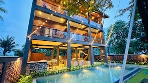 A multi-story building with a pool, outdoor seating, and string lights.