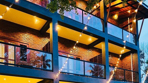 A multi-story building with a pool, outdoor seating, and string lights. - Airport Hotel Transit 98  (Katunayake)