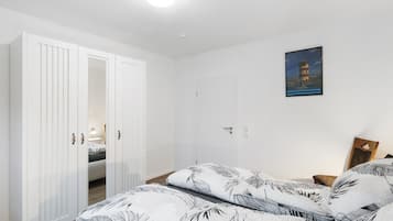 Ein Schlafzimmer mit einem Bett, einem Kleiderschrank, einem Gemälde und einer Tür.