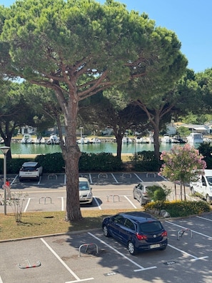 Ein Parkplatz mit Baum, eine Marina mit Booten und ein klarer Himmel.