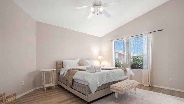 Ein Schlafzimmer mit Bett, Nachttisch, Bank und Deckenventilator.