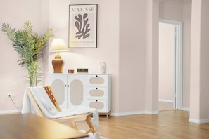 Een kamer met een witte kast, een lijstwerk, een lamp en een plant.