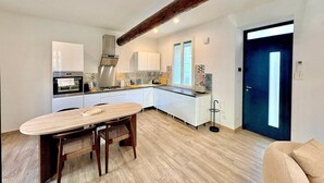 Una cocina moderna con armarios blancos, una mesa de comedor de madera y un ventanal grande.