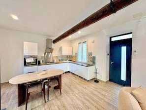 A modern kitchen with white cabinets, a wooden dining table, and a large window. - La Romaine, 2 guests, city centre, king-size bed (Nîmes)