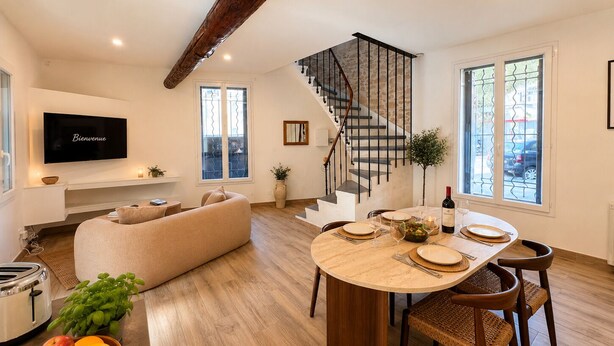 Una sala de estar moderna con un sofá, una mesa de comedor y una escalera.