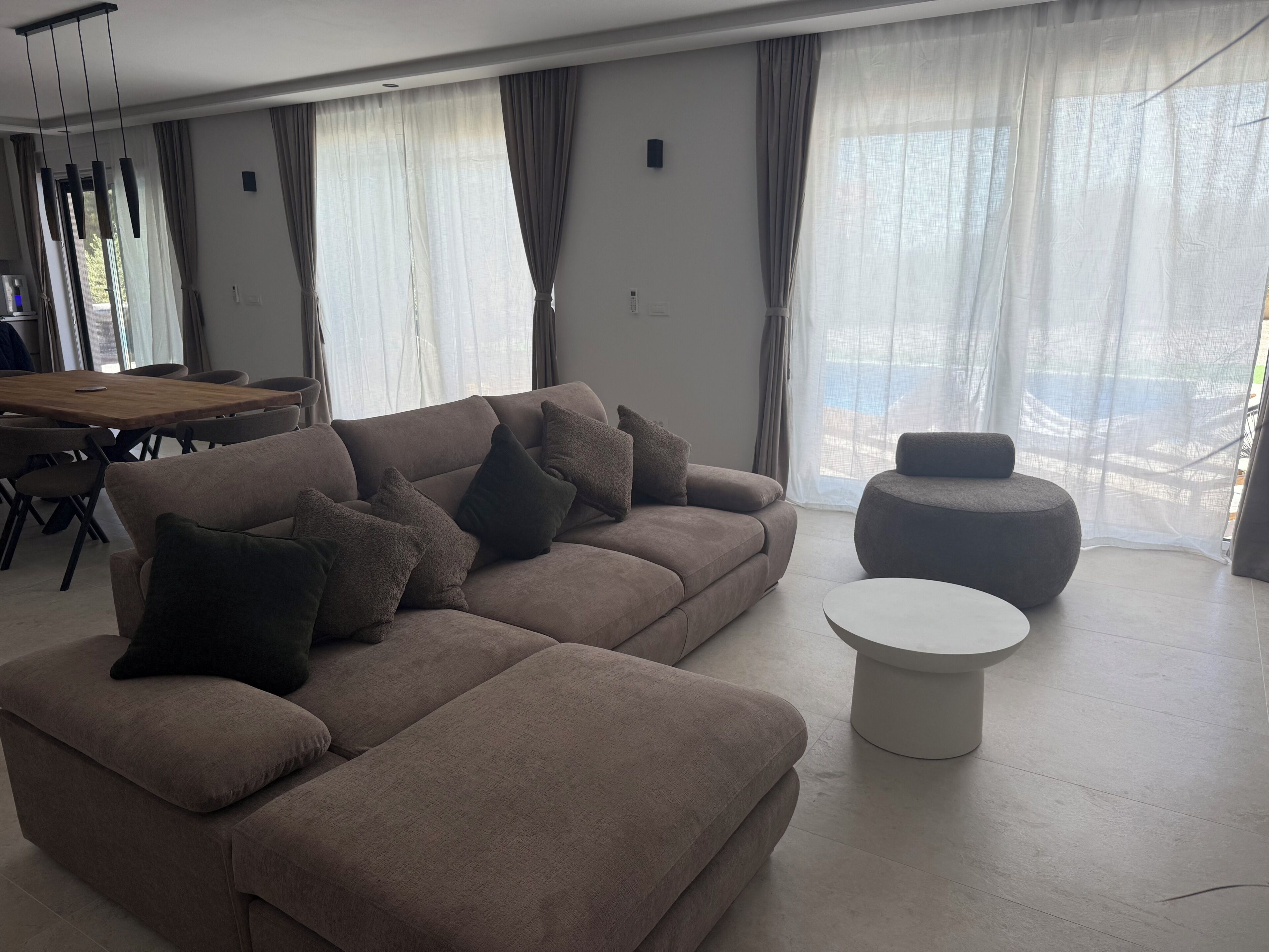 A modern living room with a sofa, ottoman, and round coffee table.