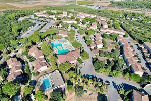 An aerial view of a residential area with a central swimming pool surrounded by houses, roads, and greenery. - La cachette du mas, 4 guests, Pool in Calvisson (Calvisson)