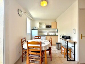 A compact kitchen with a microwave, sink, and a small refrigerator. There is a dining table with chairs and a laptop on a small table. - La cachette du mas, 4 guests, Pool in Calvisson (Calvisson)