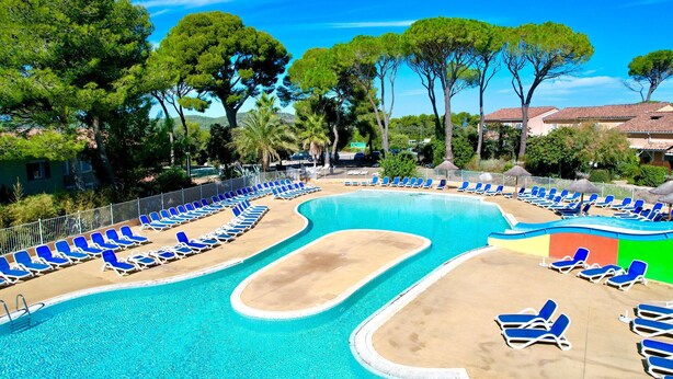 A pool with blue lounge chairs, a sandy area, and trees in the background. - La cachette du mas, 4 guests, Pool in Calvisson (Calvisson)