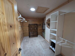 A hallway with wooden walls, a carpeted floor, a wardrobe, and a shelf unit. - River Valley Lodge - 79393 Brae Gate (Portola)