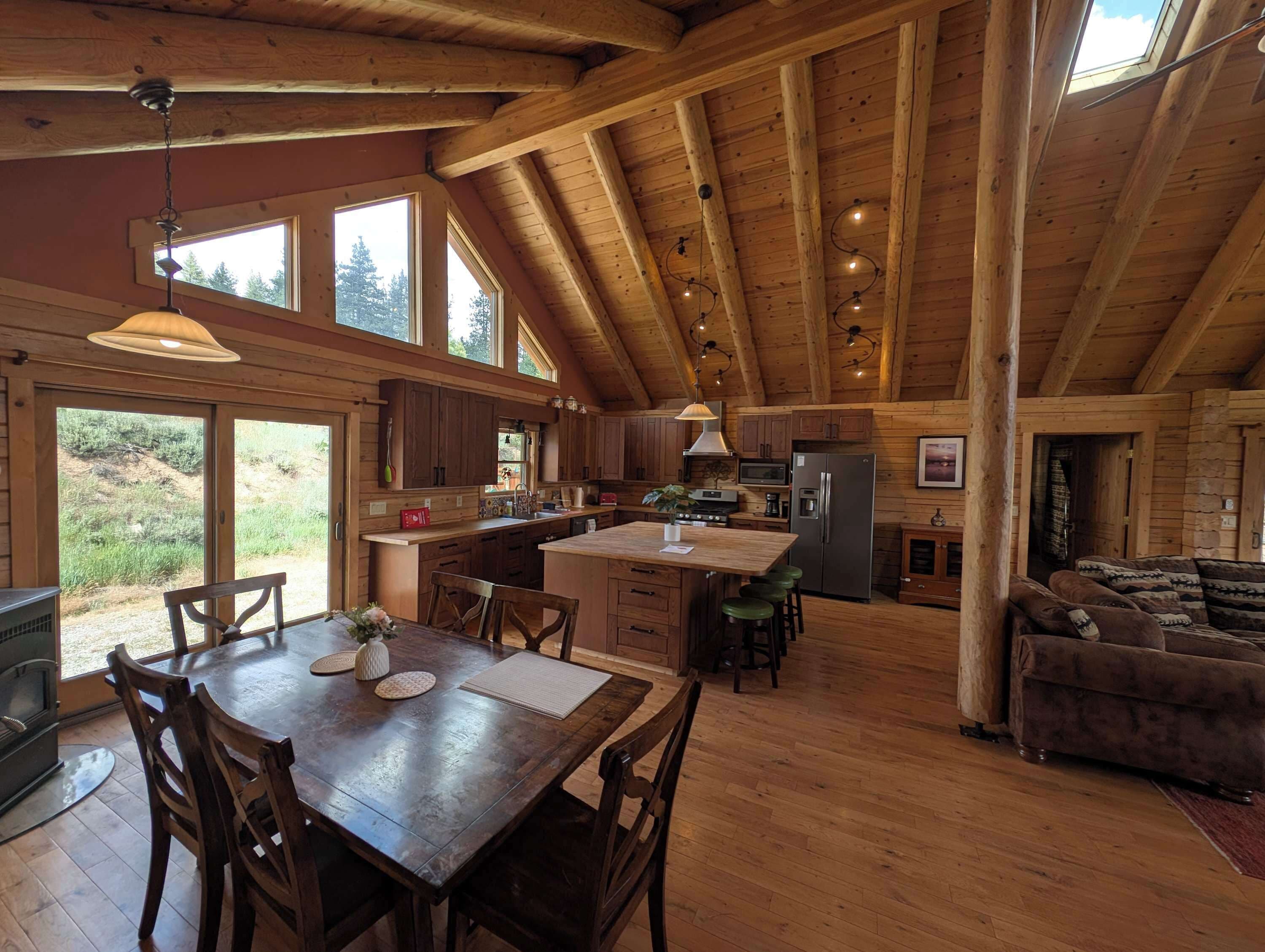 Una cocina amplia con vigas de madera, un comedor con mesa y sillas, y una sala de estar acogedora con un sofá.