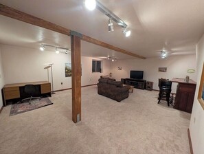 A living room with a desk, couch, TV, and speakers. - River Valley Lodge - 79393 Brae Gate (Portola)