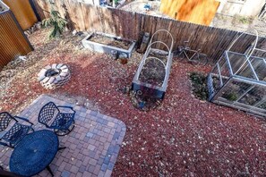A backyard with a brick patio, metal chairs, a raised garden bed, a compost bin, and a greenhouse. - NEW! Library House! AC/Grill/Near downtown. (Flagstaff)