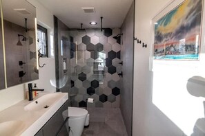 A modern bathroom with a large mirror, a shower with a glass enclosure, and a hexagonal tile pattern on the walls. - NEW! Library House! AC/Grill/Near downtown. (Flagstaff)