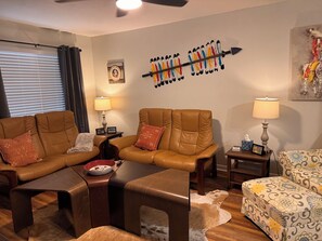 A living room with leather sofas, a coffee table, and a patterned rug. - Relaxing Renegade - 2 bedroom 1 bath condo within walking distance to FSU (Tallahassee)