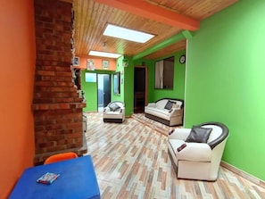 A room with a brick wall, a blue table, two white sofas, and a green wall.
