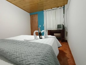 A bedroom with a bed, a television, and a bottle of champagne.