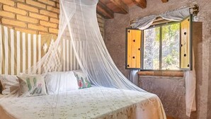Un dormitorio con una cama, una ventana con contraventanas de madera y una pared de ladrillo.