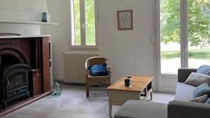 En stue med pejs, sofa, sofabord og en fletstol.