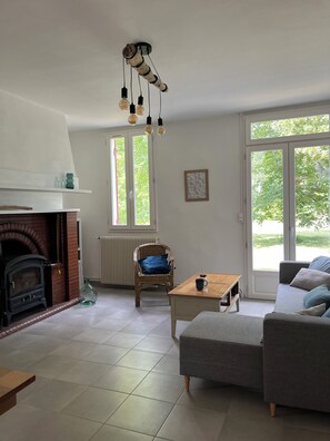 Ein Wohnzimmer mit Kamin, einer Couch, einem Couchtisch und einem Korbsessel.