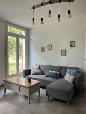 Ein modernes Wohnzimmer mit einem grauen Sofa, einem Holztisch und einer Pendelleuchte.