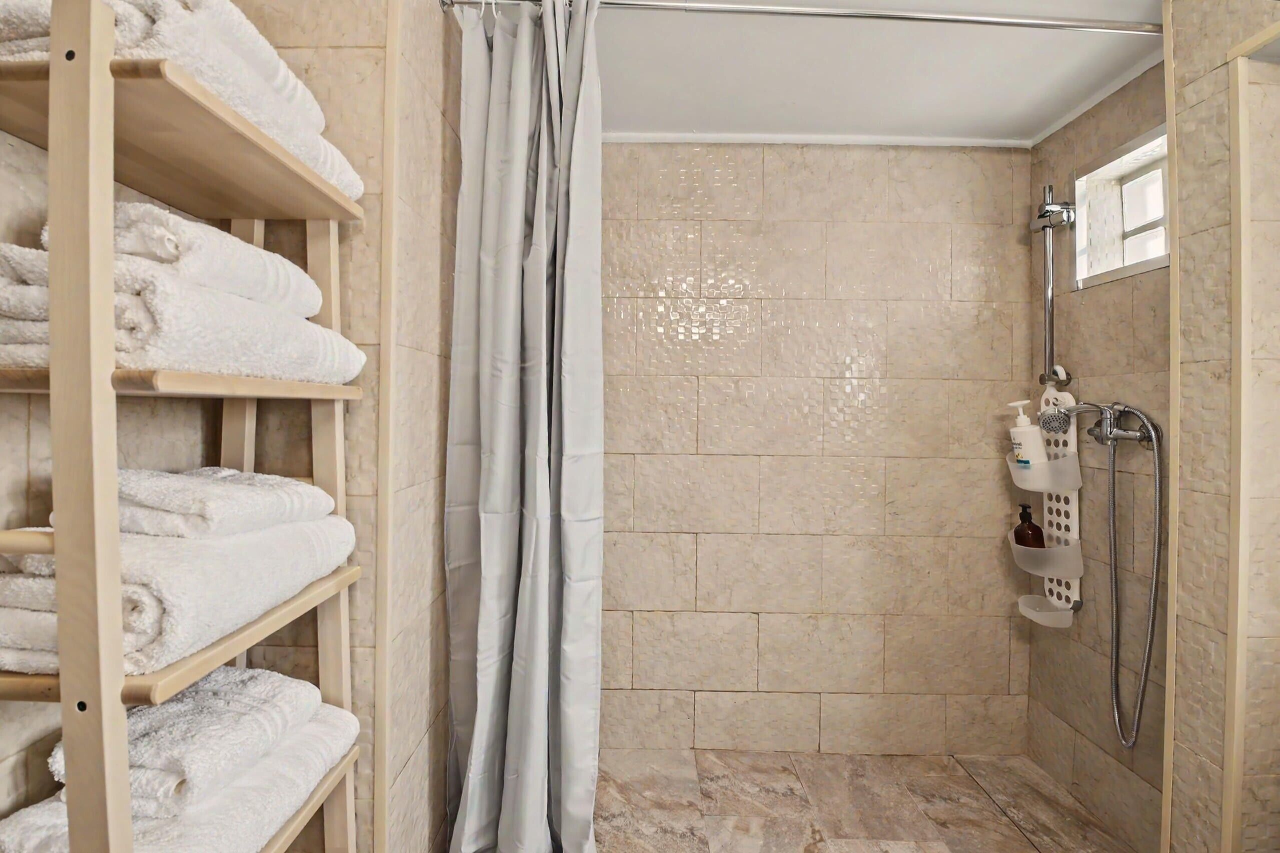 Une salle de bain avec une douche, un porte-serviettes et une étagère contenant des articles de toilette.