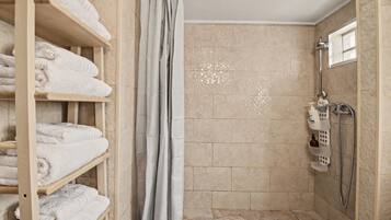 Une salle de bain avec une douche, un porte-serviettes et une étagère contenant des articles de toilette.