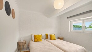 Ein Schlafzimmer mit zwei Betten, einem Fenster, einem Nachttisch und einem Teppich.
