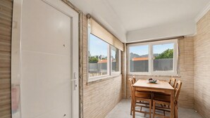 Ein Zimmer mit Esstisch, Stühlen, einer Schiebetür und großen Fenstern.