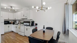 A modern kitchen with white cabinets, a stove, and a dining table with chairs. - -Cozy 2-Bedroom Retreat in Pacifica (Pacifica)