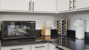 A kitchen with white cabinets, a Kenmore microwave, a spice rack, and a paper towel holder. - -Cozy 2-Bedroom Retreat in Pacifica (Pacifica)