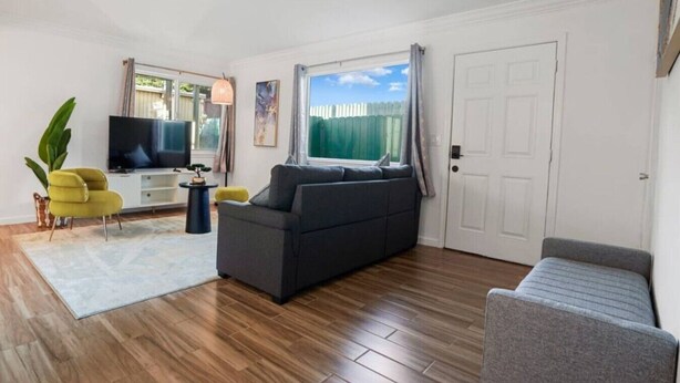A living room with a sofa, a television, a plant, and a window with curtains. - -Cozy 2-Bedroom Retreat in Pacifica (Pacifica)