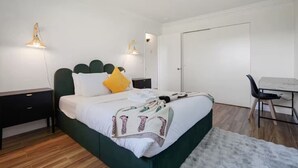 Un dormitorio con una cama, mesitas de noche, un escritorio y una silla.