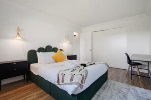Une chambre à coucher avec un lit, des tables de chevet, un bureau et une chaise.