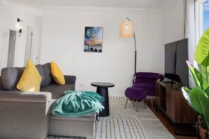 A modern living room with a sofa, armchair, and a small table. - Coastal Cozy 2BR Retreat in pacifica (Pacifica)