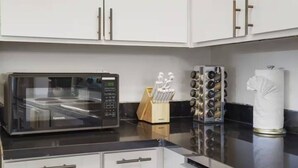 Una cocina con armarios blancos, un microondas, un estante para especias y un dispensador de toallas de papel.