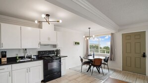 A modern kitchen with white cabinets, a black stove, and a dining area with a round table and chairs. - +Tranquil 2BR with Coastal and Mountain Views (Pacifica)