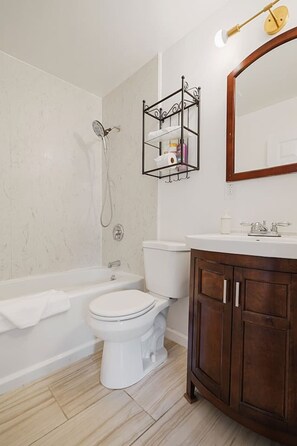 Un baño con bañera, inodoro y tocador con espejo.
