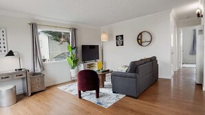 A living room with a sofa, TV, desk, and a plant. - +Tranquil 2BR with Coastal and Mountain Views (Pacifica)