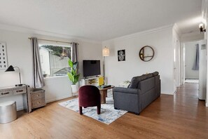 A living room with a sofa, TV, desk, and a plant. - +Tranquil 2BR with Coastal and Mountain Views (Pacifica)