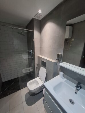 Ein modernes Badezimmer mit einer Glaskabine zur Dusche, einer Toilette und einem Waschbecken mit Spiegel.