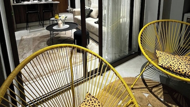 A modern living room with a sofa, a dining area with a table and chairs, and two yellow wicker chairs with leopard print cushions. - Cosy apartment Casablanca March 2 (Casablanca)