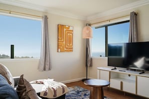 Ein modernes Wohnzimmer mit großem Fernseher, einer Stehlampe und Blick zum Himmel.