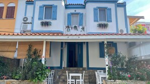A two-story building with a balcony, outdoor seating, and a stone wall. - MirAda Blue Otel Bozcaada (Bozcaada)