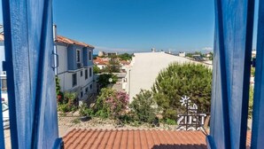 A residential area with buildings, a clear sky, and a metal gate with a sun emblem. - MirAda Blue Otel Bozcaada (Bozcaada)
