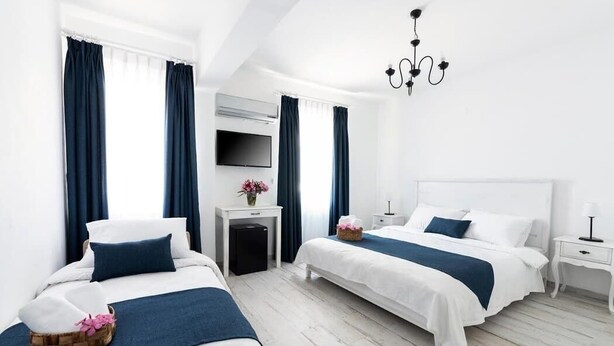 A hotel room with two beds, a TV, a desk, and a chandelier. - MirAda Blue Otel Bozcaada (Bozcaada)