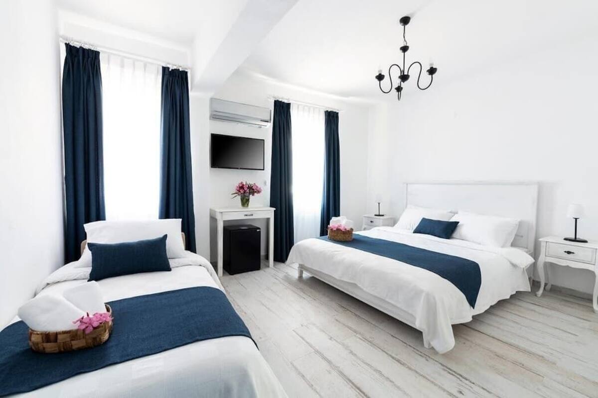 A hotel room with two beds, a TV, a desk, and a chandelier.